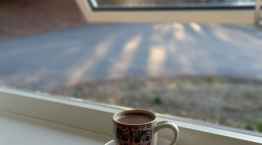 Coffee cup on a sunny window sill overlooking a forest, a calm start to a daily CBD routine