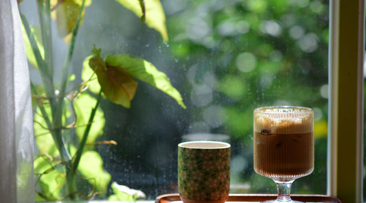 Coffee cups on a sunlit windowsill surrounded by greenery, a calm start to a morning C8 MCT oil coffee routine